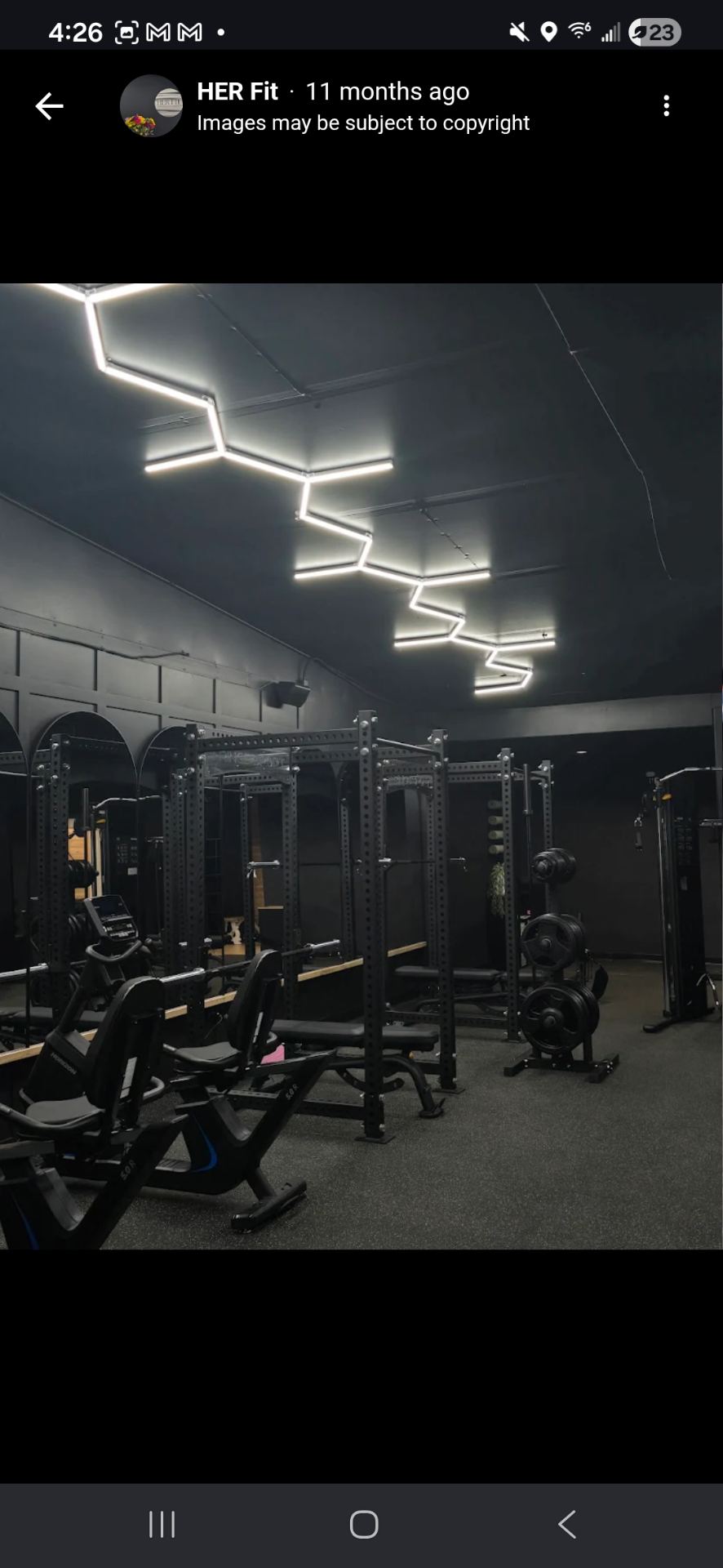 The HER Fit studio interior with squat racks and warm wood floors